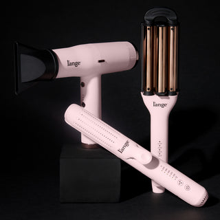 L’ange pink styling tools including airflow styler, blow dryer, and waver on black background
