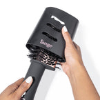 Black tear-drop brush dryer with black protective cover held by dark skin hand