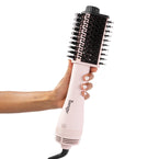 Blush tear-drop brush dryer with black bristles held by dark skin hand