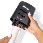 Blush tear-drop brush dryer with black protective cover held by dark skin hand