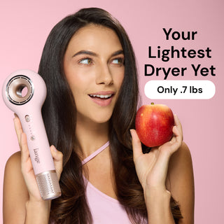 Model holding Axia blush hair dryer and apple. Text reads "Your lightest dryer yet. Oly .7 lbs"