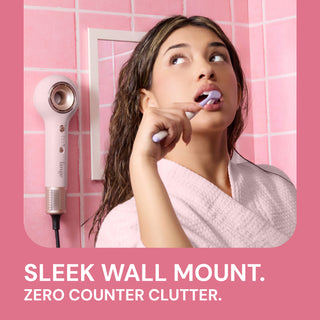 Image showing tool being mounted and styling while model is brushing teeth.  Text reads "Sleek Wall Mount. "Zero counter clutter"