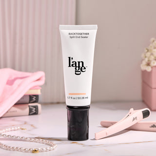 L'ange Back Together Split End Sealer tube, 1.7 fl oz (50.28 ml), on a marble surface with soft pink accents, a hair clip, and a pearl necklace in the background.