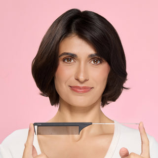 Woman holding a black metal pin-tail comb against a pink background.