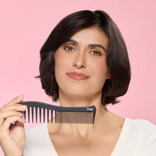 Woman holding a dual ended comb against a pink background.
