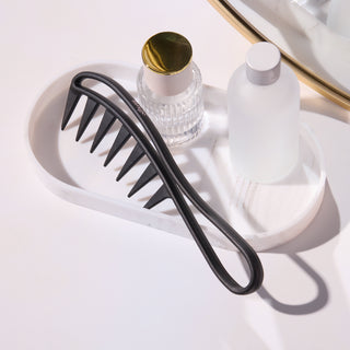 Black wide tooth detangler comb on a vanity tray 