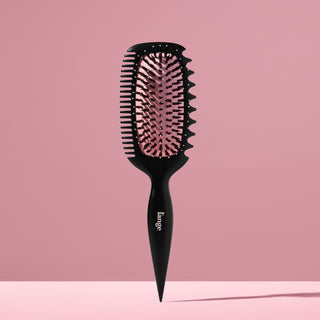 L’ange Curl Sculptor brush standing upright against a pink backdrop