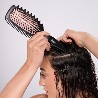model using the brush’s pointed handle to section curly hair.