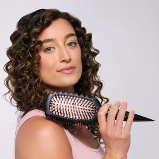 Model with curly hair holding the L’ange Curl Sculptor brush