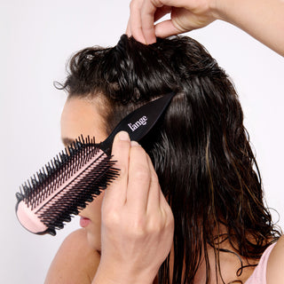 model using the brush’s pointed handle to section her hair.