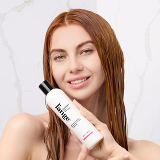 Model with wet hair holding the Everyday Daily Shampoo