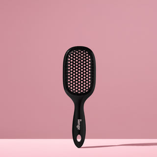 black L’ange detangling brush standing upright on pink background