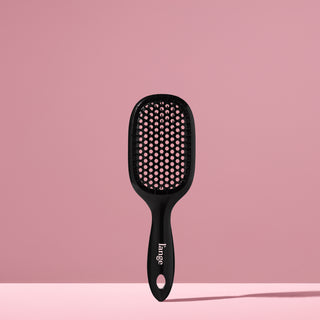 black L’ange detangling brush standing upright on pink background