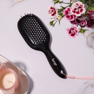 L’ange black detangling hair brush on a vanity with hair products 