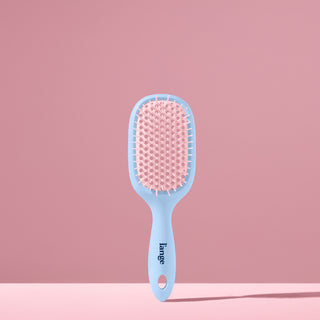 blue and pink L’ange detangling brush standing upright on pink background