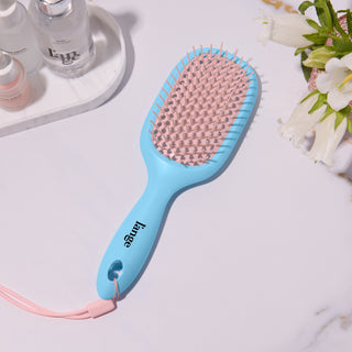 L’ange blue and pink detangling hair brush on a vanity with hair products 