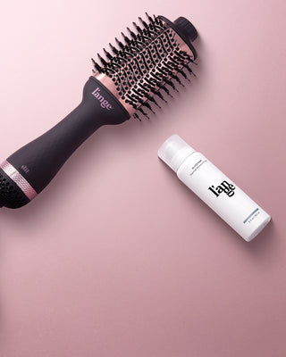 Value Set. L’ange hair products laid flat on a pink background including Le Volume 75mm (Black) and glass hair