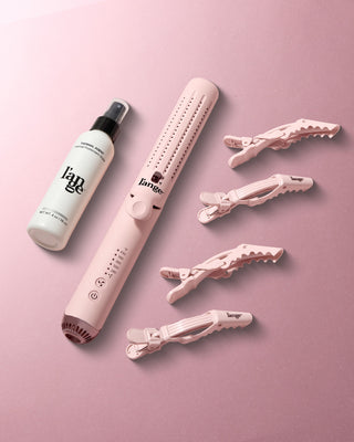 Thermal styling brush set including a protective spray bottle, a pink styling brush with adjustable temperature settings, and four matching hair clips, arranged on a soft pink surface.