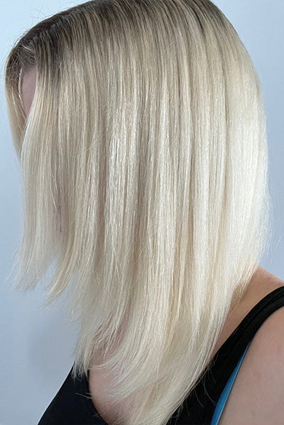 A person with straight, shoulder-length platinum blonde hair, styled with a side part, wearing a black top.