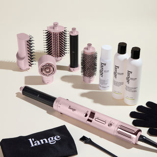 The Frizz-Free Routine Value Set, featuring the blush TurboStyle Styling & Drying System, Top Coat, Frizz Care Shampoo, and Frizz Care Conditioner on a beige background