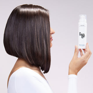 woman holding glass hair bottle