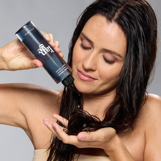 Woman applying hair treatment "Hydro Therapy" onto her wet hair.