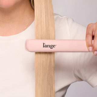 Person using a blush L’ange Le Ceramique to straighten long blonde hair.