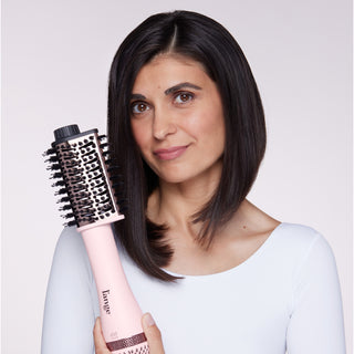 Woman holding a blush L’ange volumizing brush, showcasing sleek, straight hair.