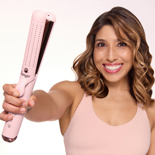 Smiling individual showcasing a pink hair styling tool with wavy, styled hair.