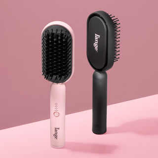 Blush and black L’ange heated brushes displayed upright on a pink background.