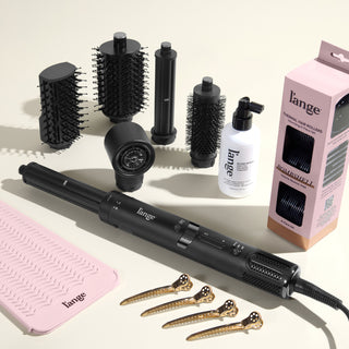 The Bombshell Blowout Value Set, featuring a Black TurboStyle, Gloss Shock, Thermal Hair rollers, Heat resistant mat, and precision metal sectioning hair clips, displayed on a beige background
