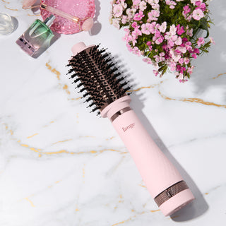 Blush and rose gold L’ange round brush styling tool on a marble surface with flowers and beauty items. 60MM