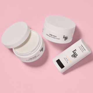 L’ange pomade collection displayed on a pink background, featuring Pure Shape Sculpting Pomade Paste in an open jar, Pure Hold Defining Pomade Cream in a closed jar, and Pure Polish Smoothing Pomade Stick.