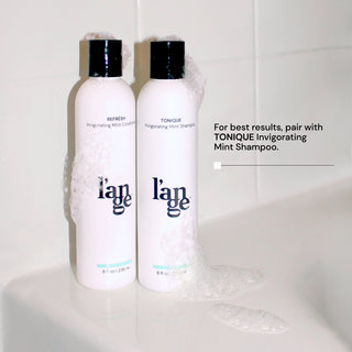 Two bottles of shampoo and conditioner with soap over them with copy saying, for best results, pair with Tonique Invigorating Mint Shampoo.