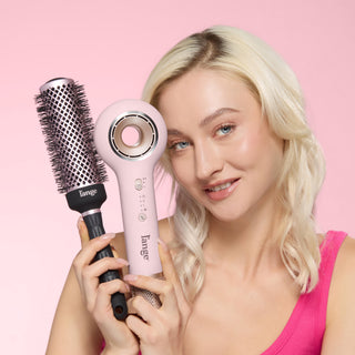 Model holding round brush and blow dryer to style hair together. 