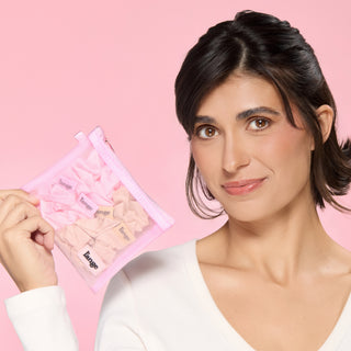 Model holding a pink mesh pouch filled with blush and champagne L’ange satin scrunchies