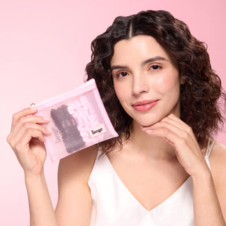 Model holding a pink mesh pouch filled with blush and black L’ange satin scrunchies