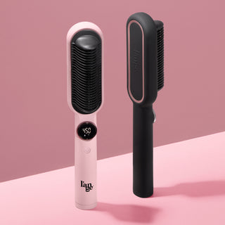 Blush and black heated paddle brushes by L’ange displayed upright against a blush background.