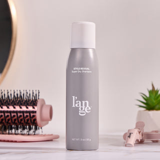 A bottle of Style Revival on a vanity with different L'ange products around it. 
