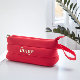 Red L’ange zippered cosmetic bag with gold logo and wrist strap on a white surface.