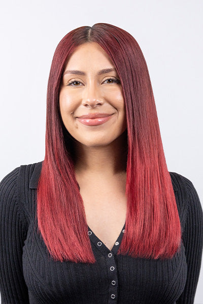 Smiling person with long, straight red hair wearing a black ribbed top.