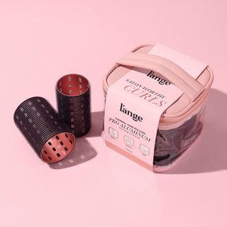 A collection of black thermal hair rollers and case, arranged on a pink background