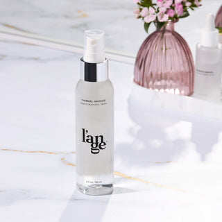 L’ange Thermal Magique heat and humidity tamer bottle on a marble surface with a vase and mirror in the background.