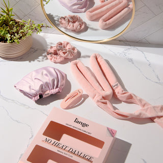 Velvet Heatless Curls Set on a vanity.  Set includes a velvet curling rod, an adjustable bonnet, two velvet scrunchies, and a hair clip 