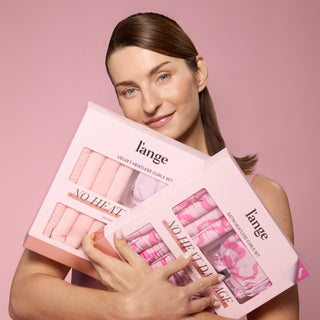 model holding two sets of heatless curls, one sating and one velvet