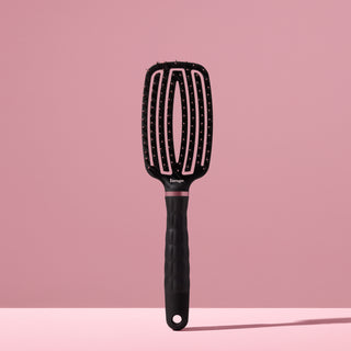 black L’ange vented paddle brush with nylon bristles standing upright on pink background