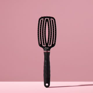black L’ange vented paddle brush with nylon bristles standing upright on pink background
