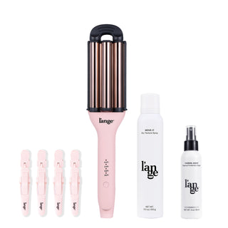 Pink barrel hair styling tool with temperature settings, accompanied by five pink hair clips, a bottle of move-it dry texture spray, and thermal protectant spray.