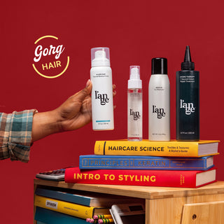 L'ange hair products arranged on stacked books against a solid red background.