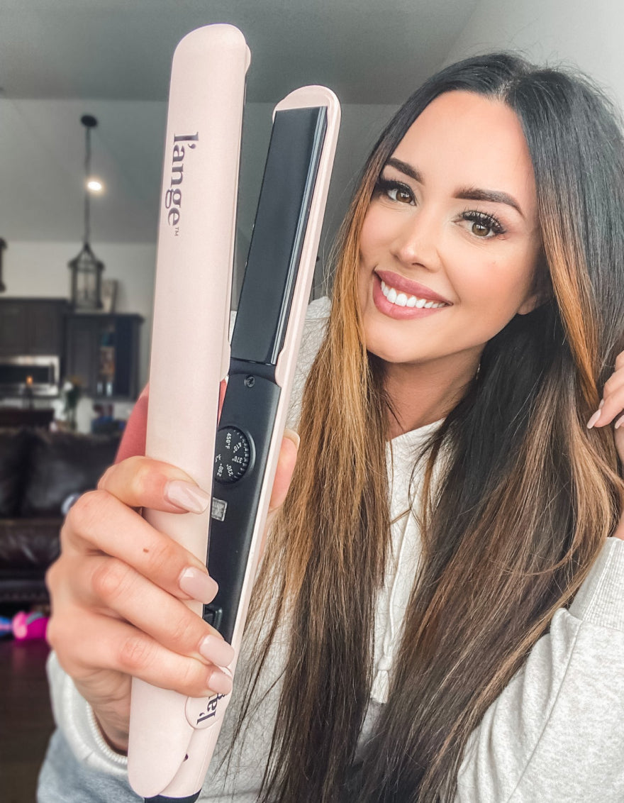  A smiling woman holding up her Le Ceramique flat iron used to straighten her hair